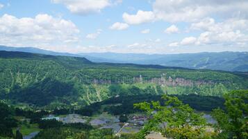 Une vue panoramique d’un paysage montagneux, avec une rivière et de petits bâtiments dans la vallée.