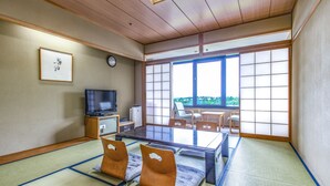 Um quarto japonês tradicional com tatames, uma mesa baixa e uma televisão.