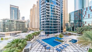 A rooftop pool area with lounge chairs, a central pool, and surrounding high-rise buildings. - Maison Privee - Stunning Apartment w/ Dubai Marina View (Dubai)