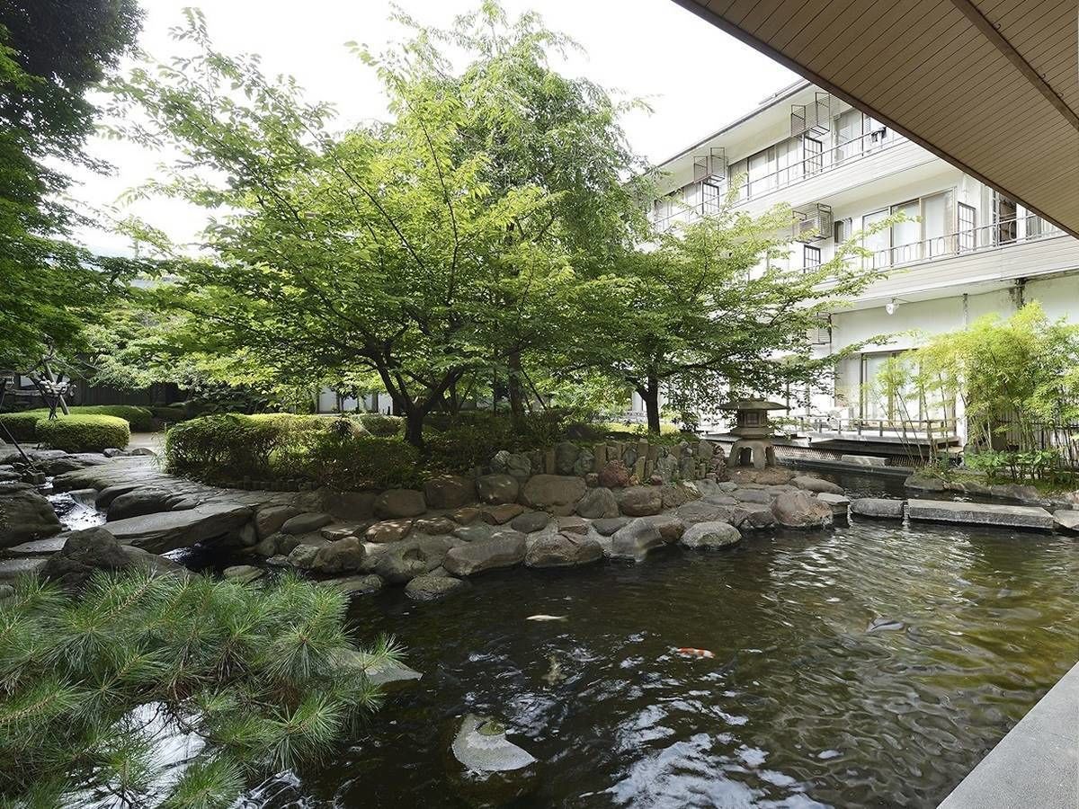 A tranquil garden with a koi pond, surrounded by rocks and lush greenery.