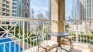 A balcony with a pool, a table, and chairs. - Maison Privee - Radiant Urban Retreat with Iconic Burj Khalifa Vws (Dubai)