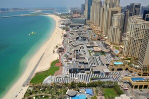 Vista aérea de una ciudad costera con playa, edificios altos y zona de piscina.