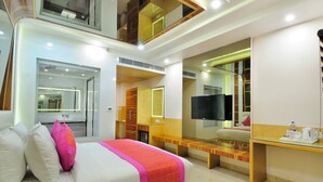 A hotel room with a bed, a desk, a mirror, and a TV. - The Gold Regency (New Delhi)