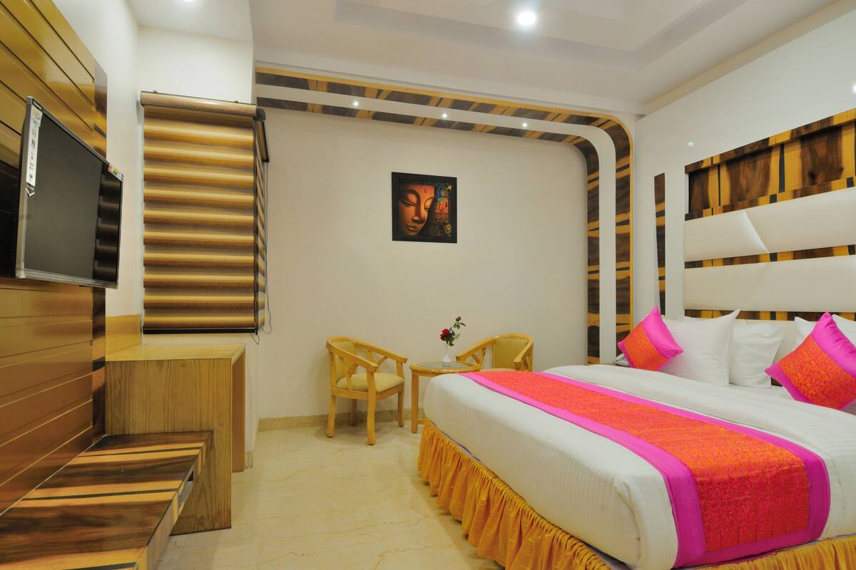 A hotel room with a bed, a desk, a chair, a TV, and a Buddha painting.