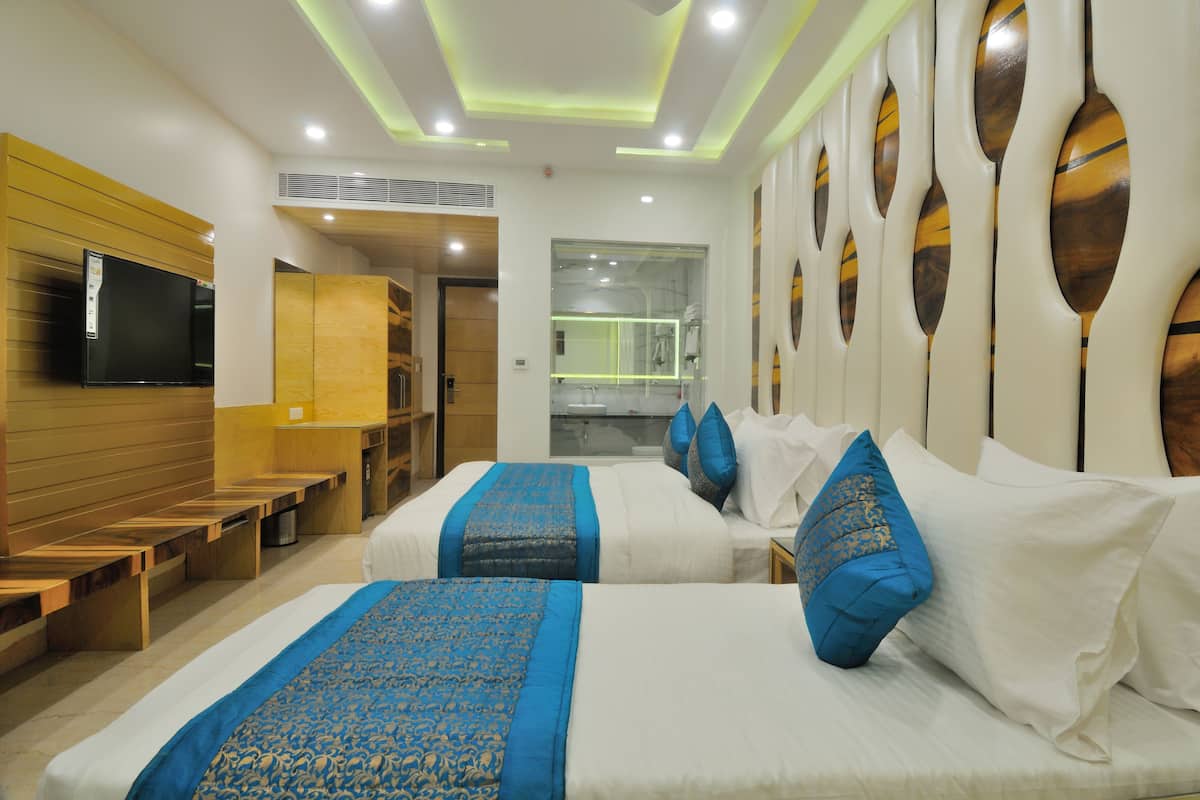 A hotel room with two beds, a TV, a mirror, and a wooden bench area.