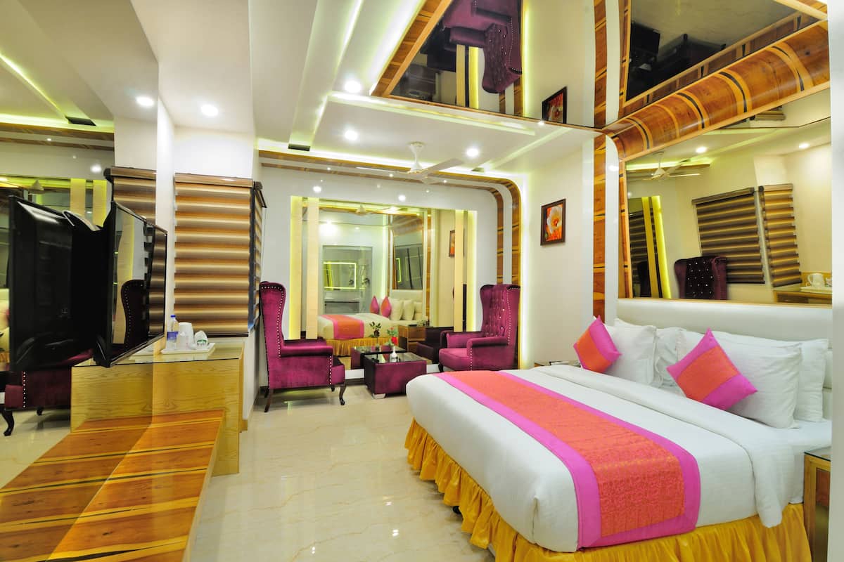 A hotel room with a large bed, a TV, a desk, and a chair.