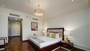 A spacious bedroom with a large bed, bedside lamps, a nightstand, and a wooden floor. - Maison Privee - Charming Apt with Arabesque Sea View on the Palm Jumeirah (Dubai)