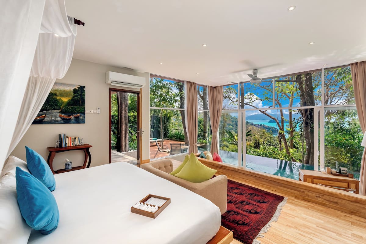 Une chambre avec un grand lit, une vue sur la piscine et un coin repas.