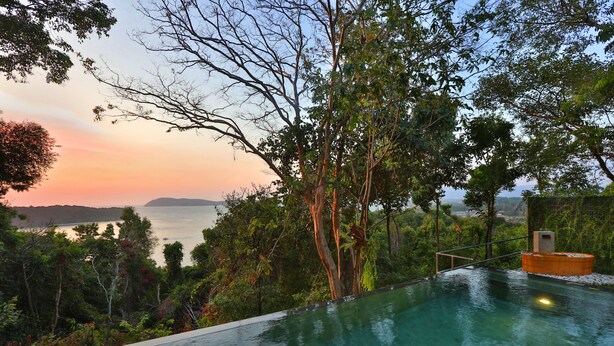 An infinity pool with a view of the sea and hills at sunset. - Ambong Pool Villas (Langkawi)