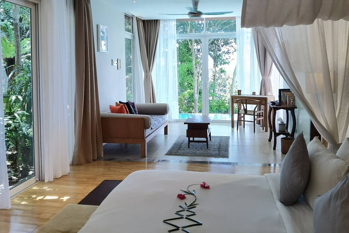 A spacious bedroom with a large bed, a sofa, and a dining area.