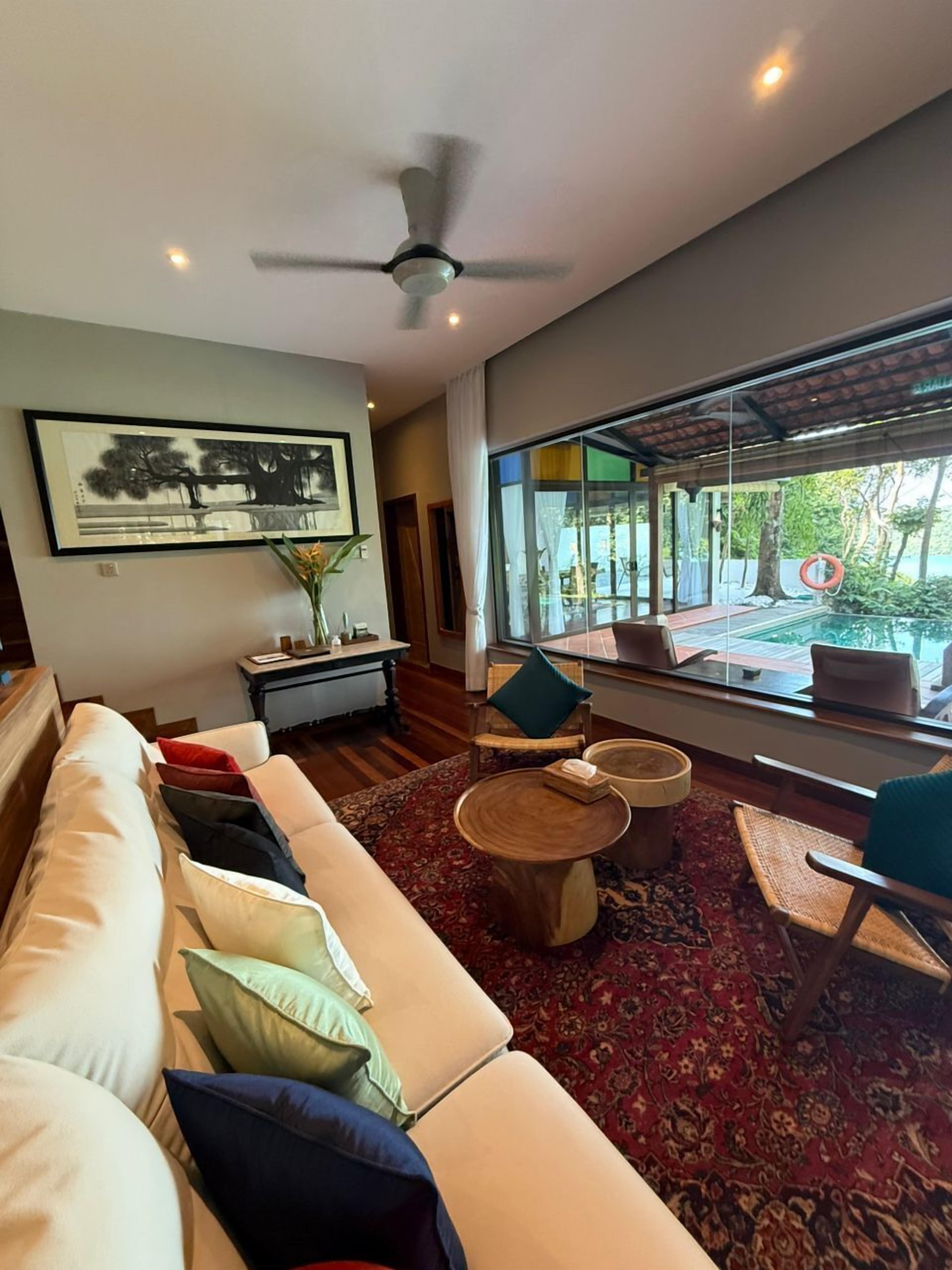 A modern living room with a large sofa, a coffee table, and a view of the outdoors through large windows.