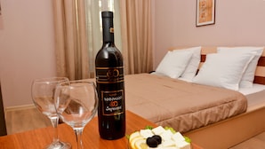 A hotel room with a bed, a table with a bottle of wine, two glasses, and a plate of cheese and olives. - Istanbul Hotel (Tbilisi)