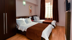 A hotel room with two beds, a wardrobe, a television, and a window with curtains. - Istanbul Hotel (Tbilisi)