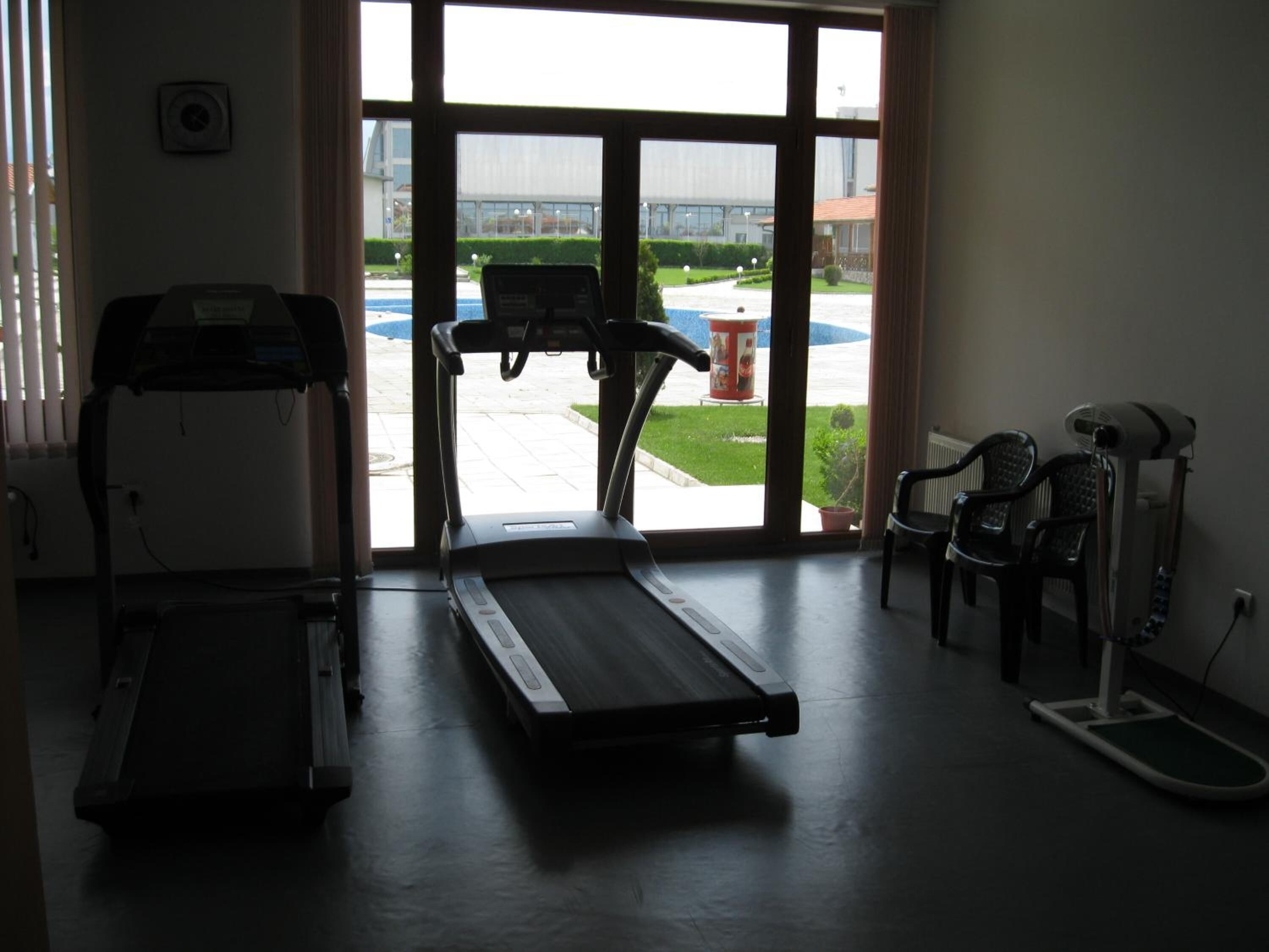 Un gimnasio con cintas de correr, una bicicleta estática y una máquina de remo.