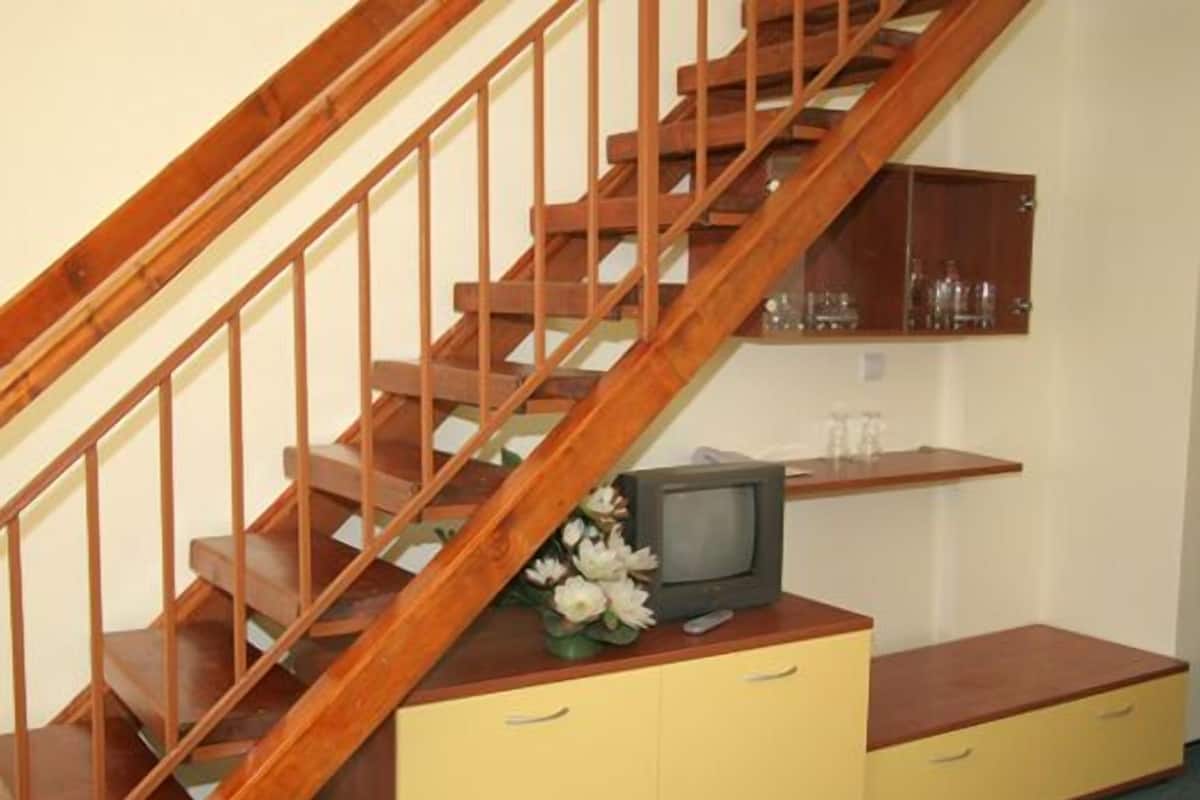 A wooden staircase with a television on a yellow cabinet.