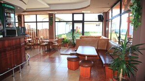 Un restaurante con barra, asientos y ventanas amplias.