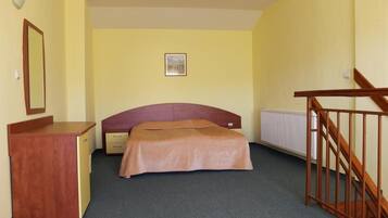 Un dormitorio con cama, escritorio, radiador y una escalera.