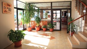 Un vestíbulo amplio con una escalera, plantas en macetas y un gran ventanal que deja entrar luz natural.