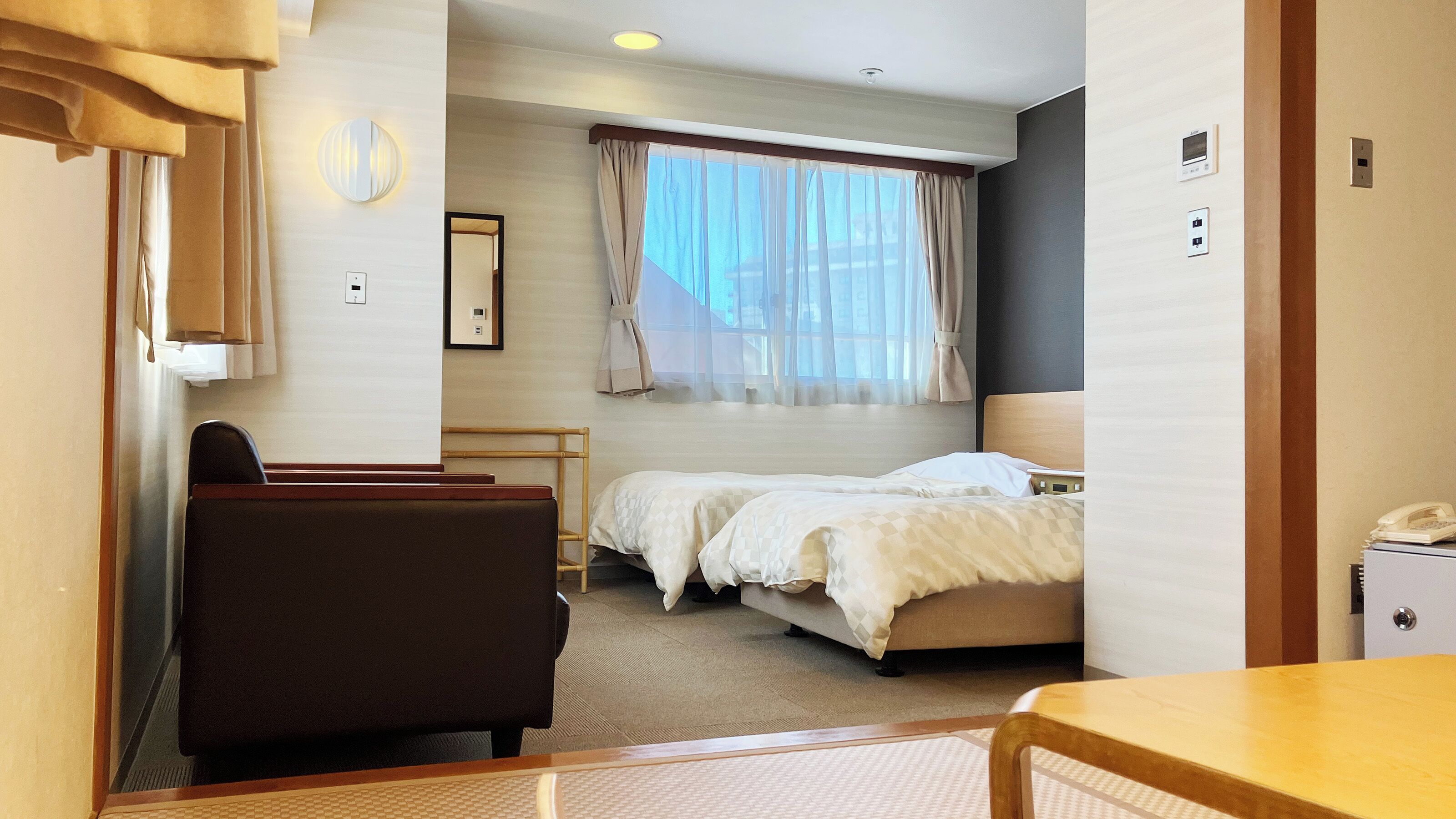 Ett hotellrum med en säng, ett skrivbord, en stol och ett litet bord.
