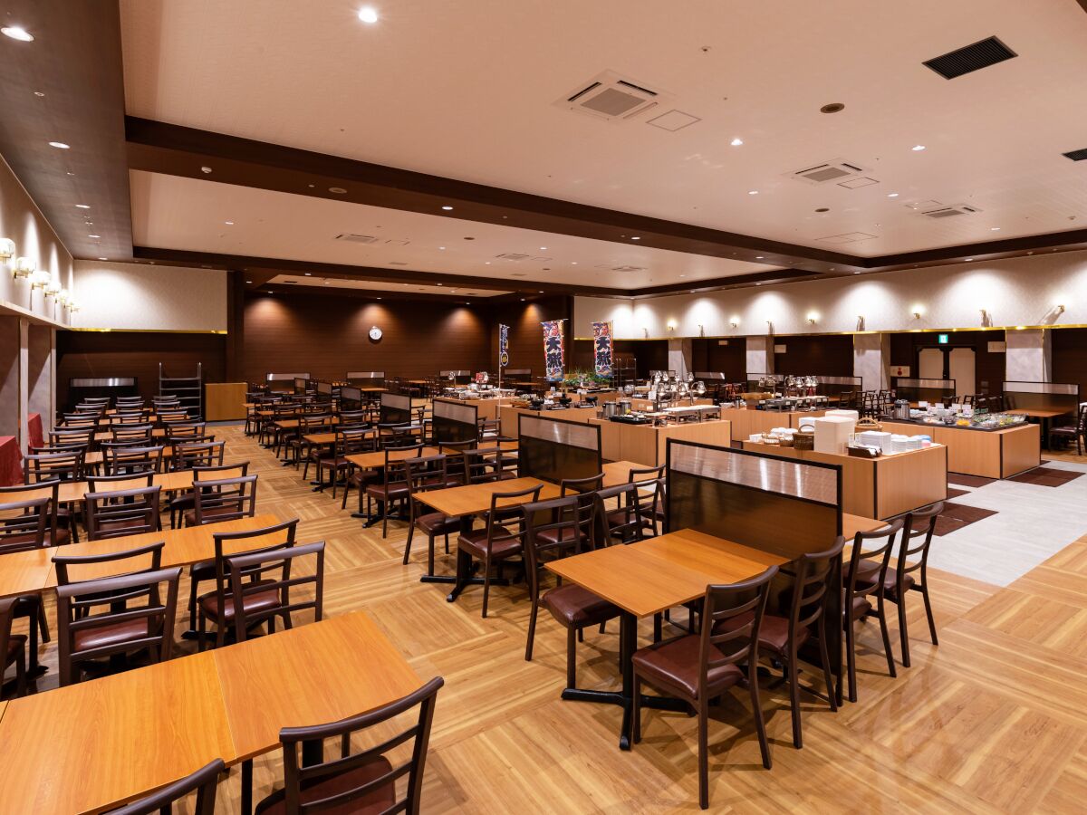 Um restaurante espaçoso com várias mesas e cabines, um balcão central e piso limpo e bem cuidado.