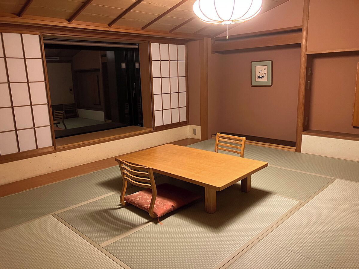 Una habitación japonesa tradicional con suelo de tatami, una mesa de madera y puertas correderas shoji.