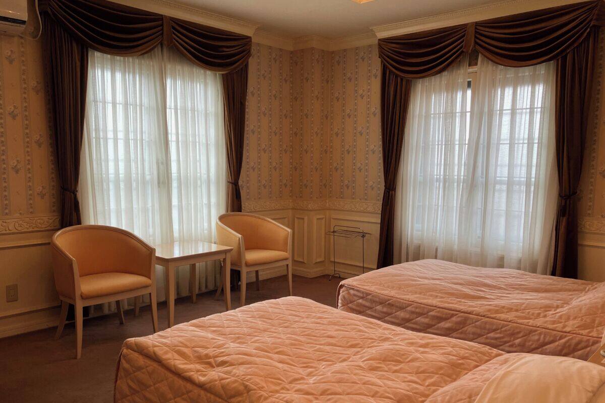 Une chambre d’hôtel avec deux lits, une petite table et deux chaises.