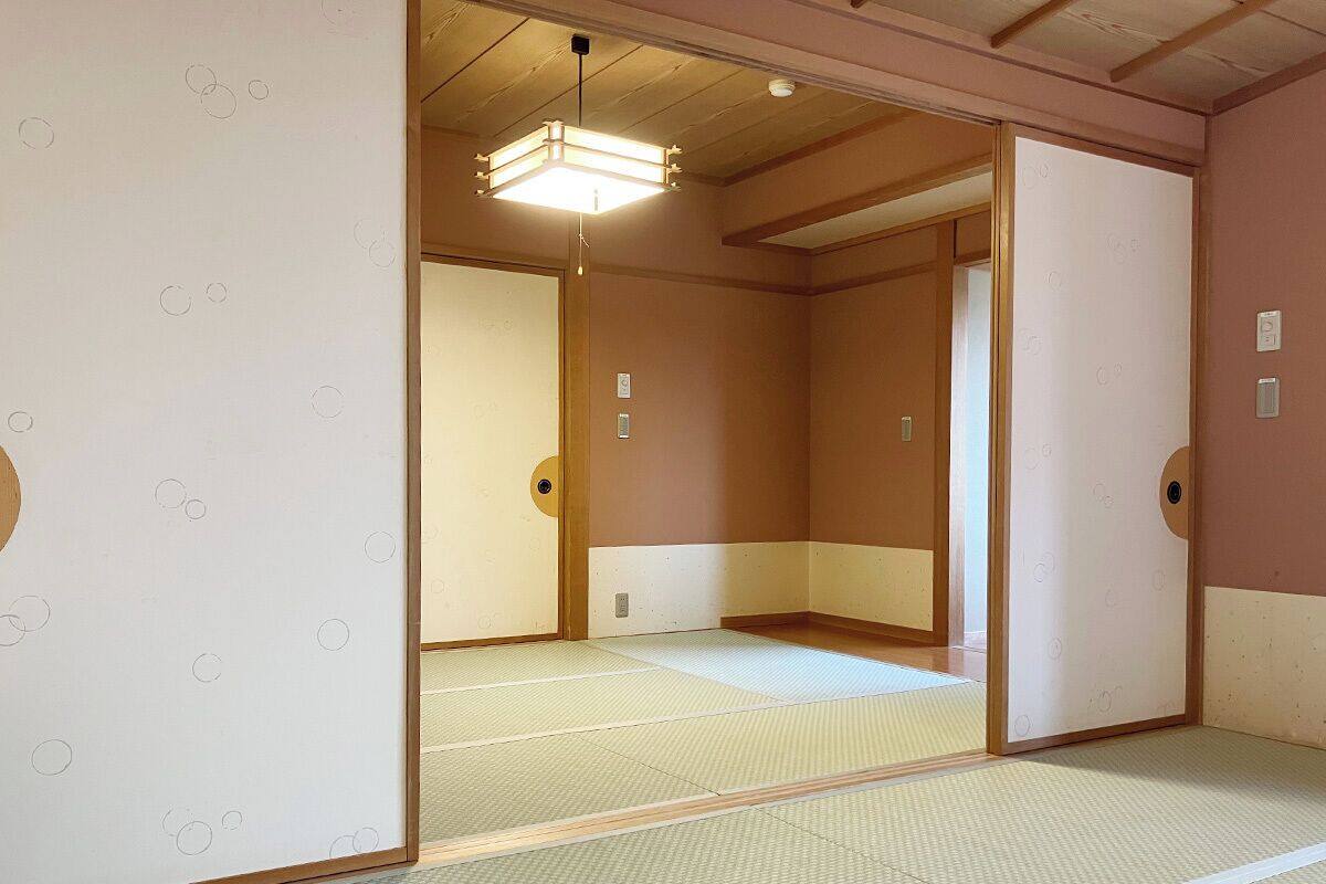 Une pièce de style japonais traditionnel, avec un sol recouvert de tatamis, des portes coulissantes et un luminaire au plafond.