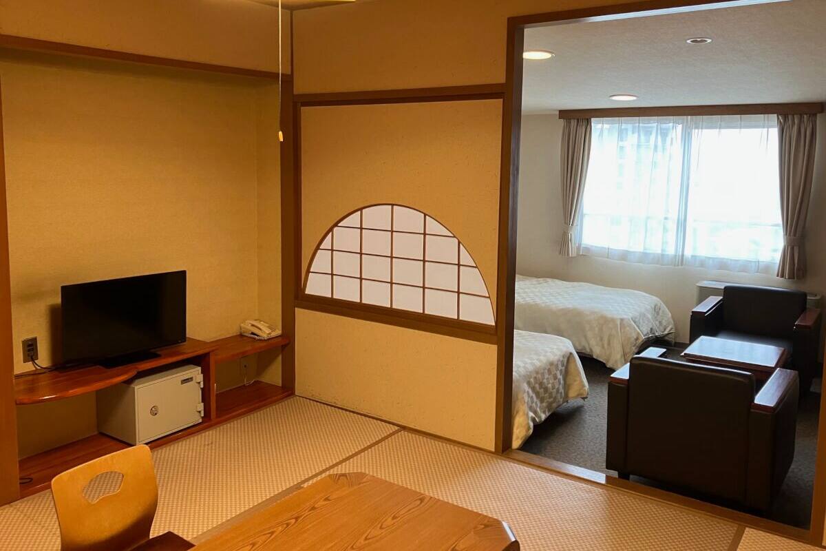 Une chambre d’hôtel équipée d’une télévision, d’un bureau avec un téléphone, d’un lit, d’une chaise et offrant une vue sur l’extérieur par une fenêtre.