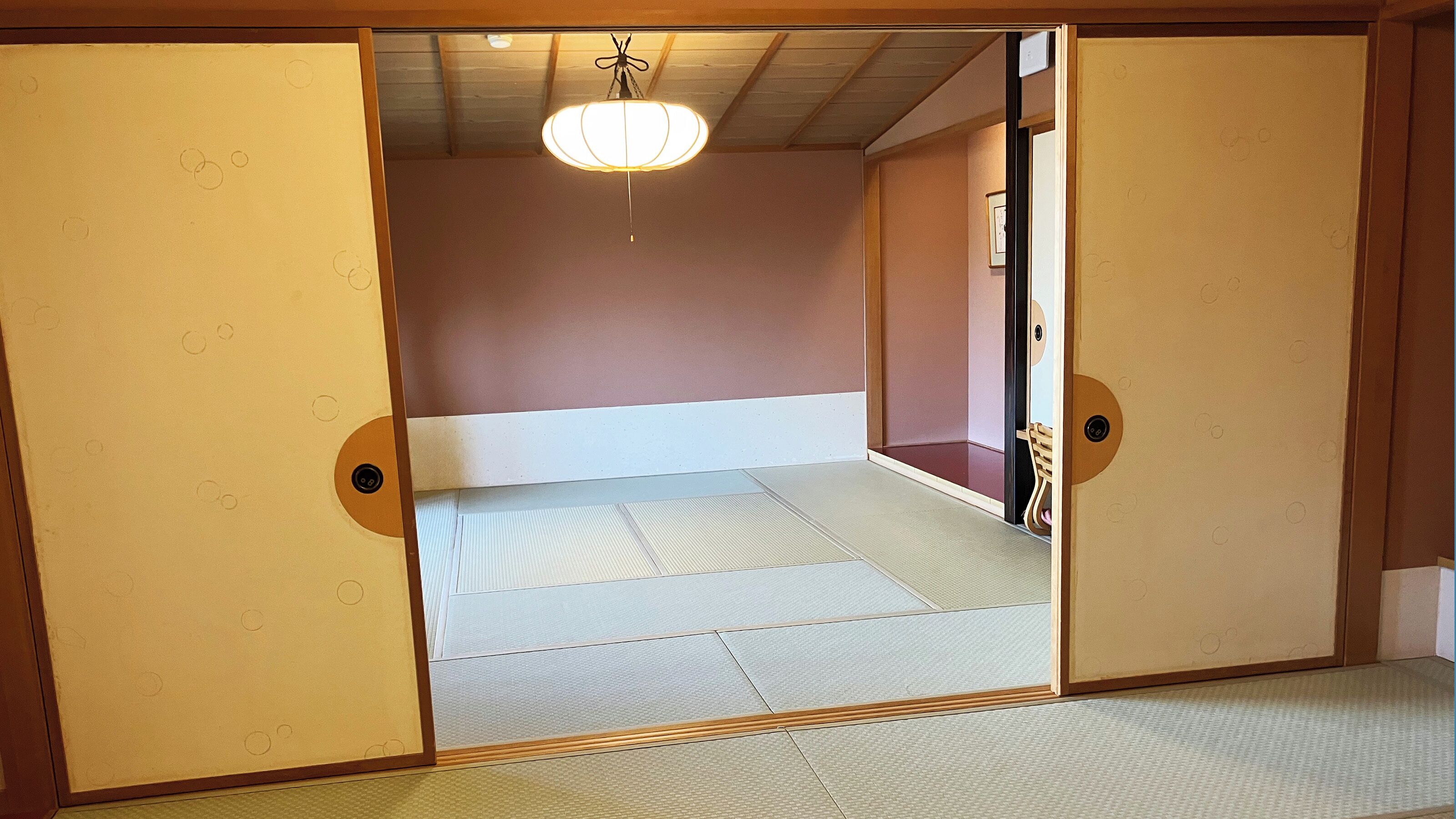 Ett traditionellt japanskt rum med tatamimattor på golvet, en låg säng och skjutdörrar.
