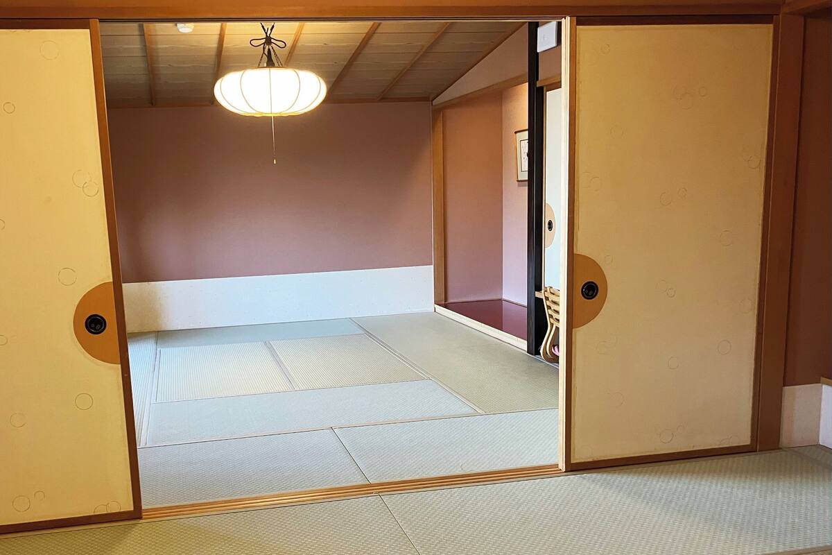 Une pièce de style japonais traditionnel, avec un sol recouvert de tatamis, un lit bas et des portes coulissantes.