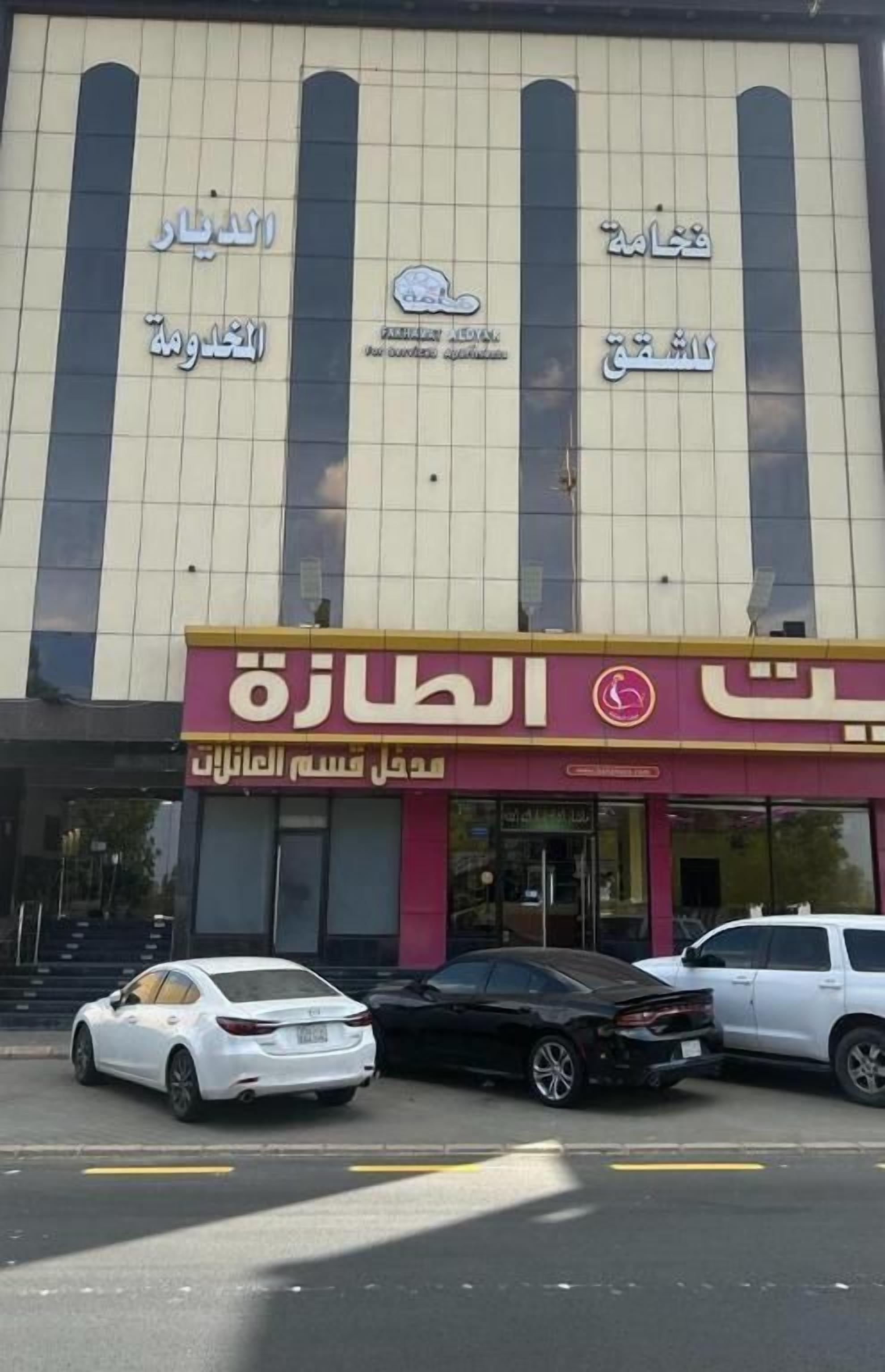 A building with multiple signs, including one for a bank and another for a restaurant. There are cars parked in front.