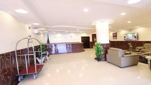 Vestíbulo de hotel con mostrador de recepción, zona de estar y una planta.