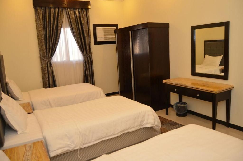 Habitación de hotel con dos camas individuales, un escritorio, un armario, un espejo y un equipo de aire acondicionado.