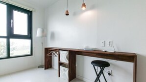Une cuisine moderne dotée d’un plan de travail en bois, d’un luminaire suspendu et d’une fenêtre avec des stores.
