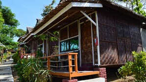 Ein Holzhaus mit einem Reetdach, einer Holzveranda und einem Ziegelkeller.