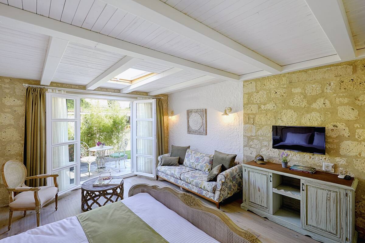 A cozy room with a bed, a sofa, a television, and a table.