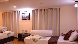 Habitación de hotel con dos camas, una mesita de noche, un cuadro enmarcado en la pared y una ventana con cortinas.