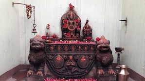 Un altar de templo con una estatua de deidad, dos estatuas de leones y una olla de cobre.