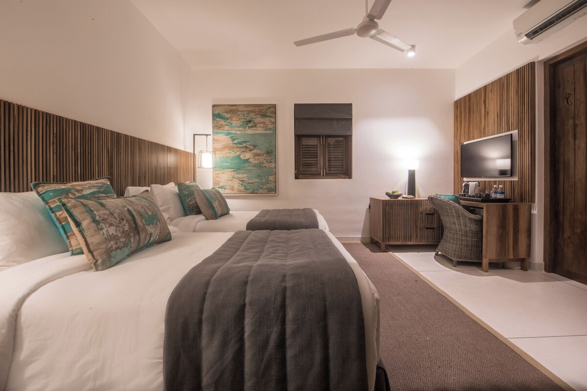A modern hotel room with a large bed, a desk with a chair, a flat-screen TV, and a ceiling fan.