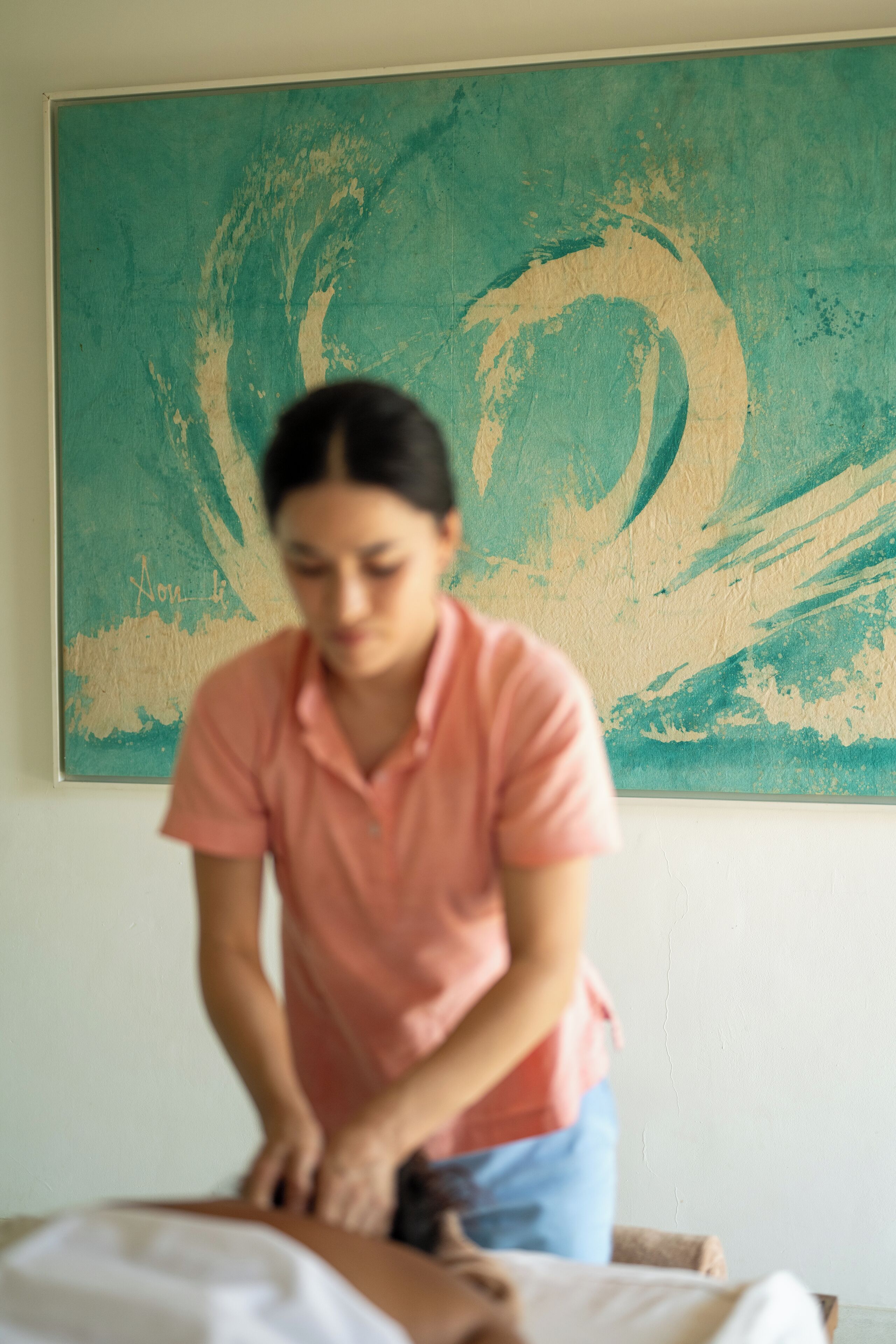 Una sesión de masoterapia en una habitación con un cuadro abstracto grande en la pared.