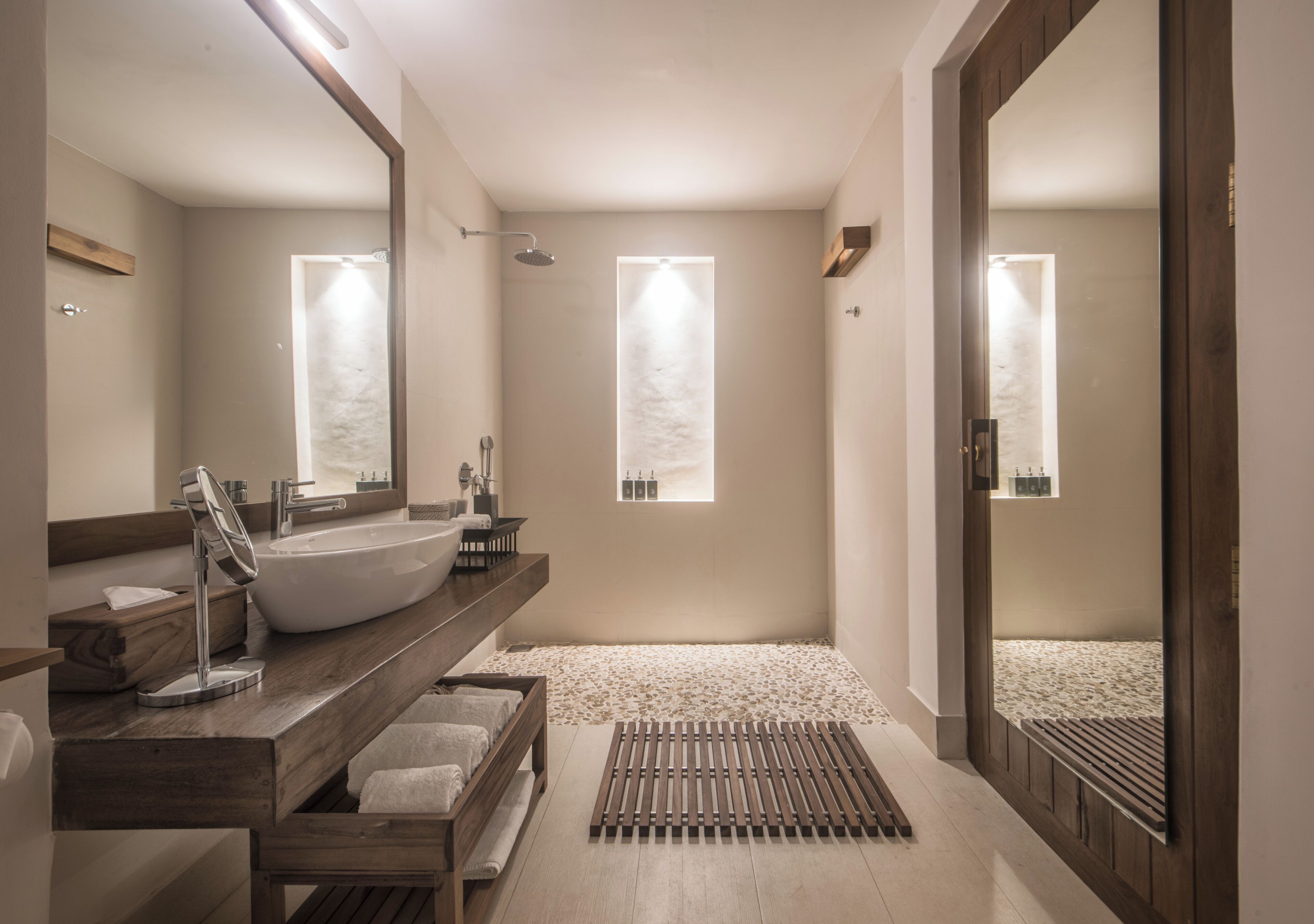 Un baño moderno con un lavamanos grande, tocador de madera y ducha a pie.