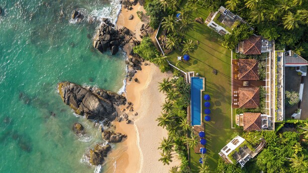 An aerial view of a coastal property with a swimming pool, beach, and lush greenery. - Kumu Beach (Balapitiya)
