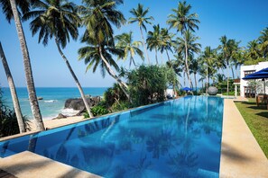 Una piscina al aire libre, sombrillas, sillones reclinables de piscina