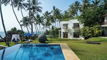 A pool with clear blue water, surrounded by a well-maintained lawn and palm trees.