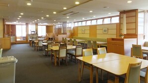 A dining area with multiple tables and chairs, a trash bin, and a counter with a display. - Itoen Hotel Atamikan (Atami)