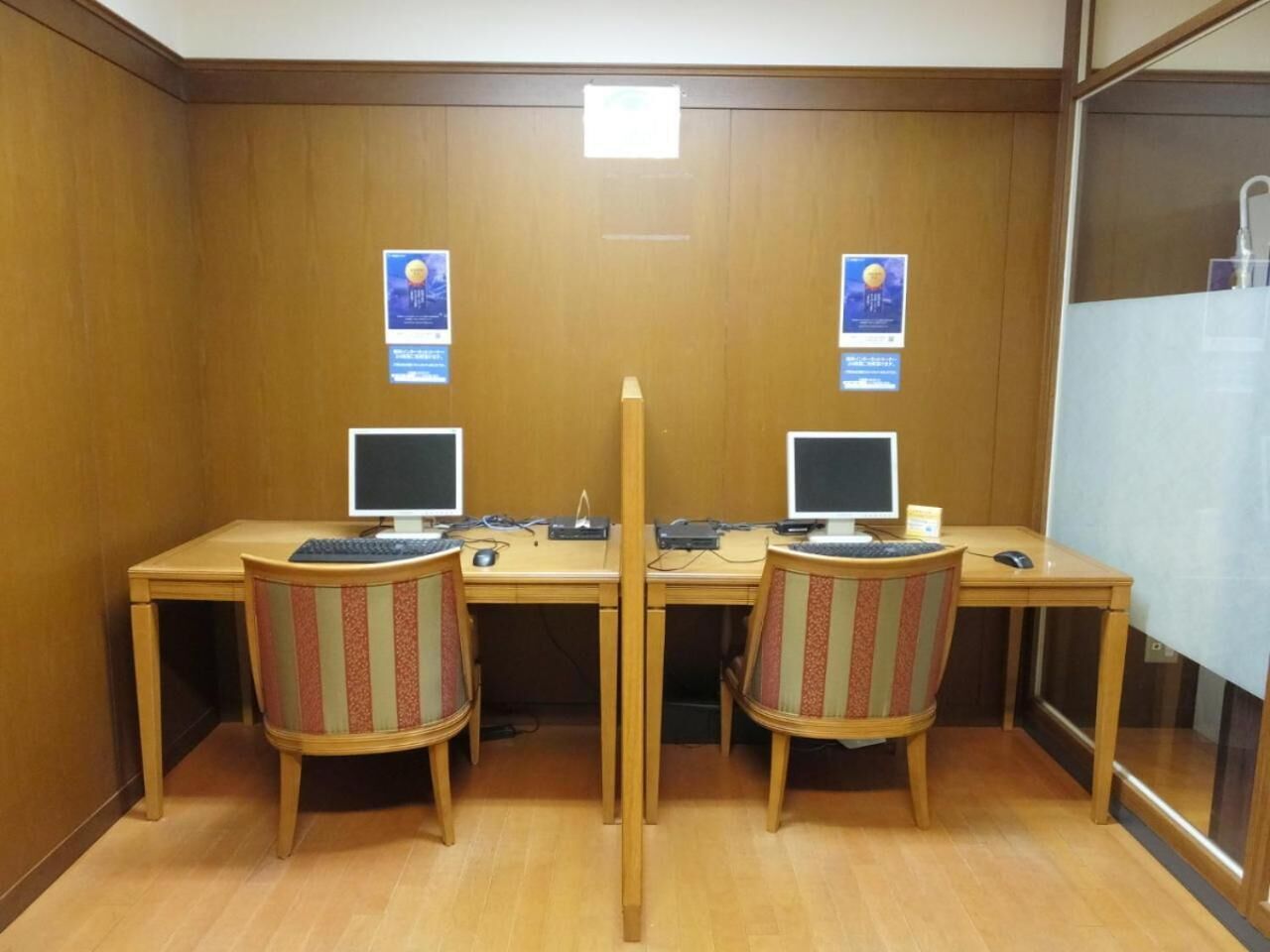 A conference room with two desks, each with a computer and a chair.