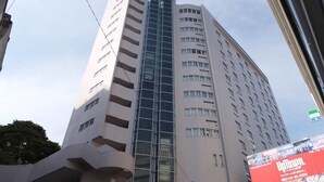A tall, modern building with a curved facade and multiple balconies. - Itoen Hotel Atamikan (Atami)