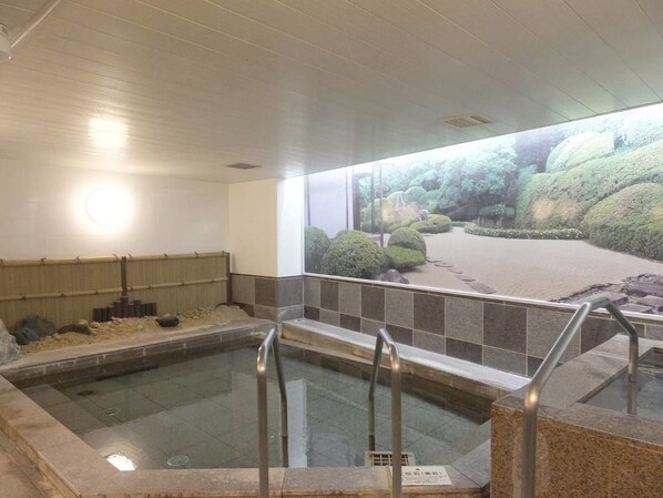 A hot spring area with a view of a landscaped garden through a large window.