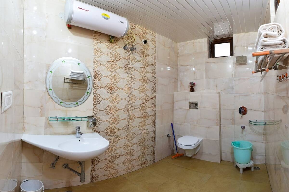 Un baño con lavamanos, espejo, inodoro, ducha y toallero.