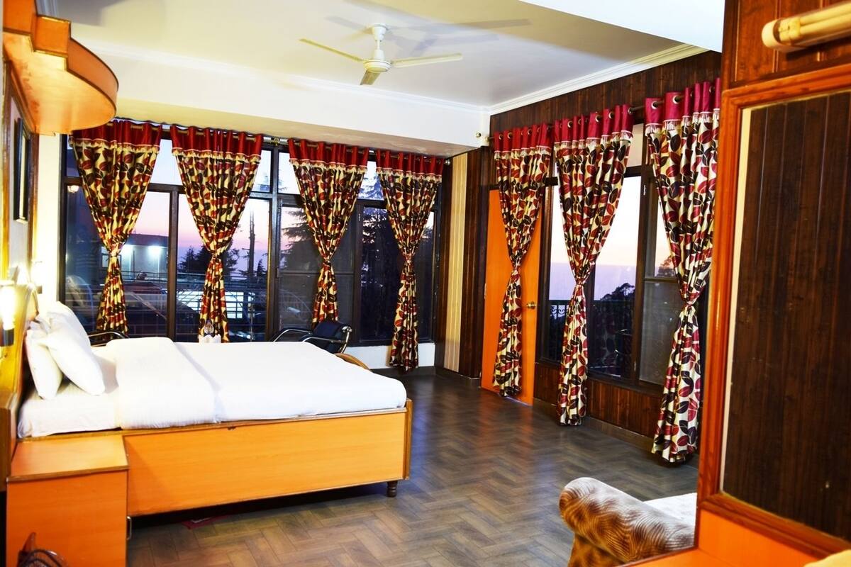 Una habitación de hotel con cama, una silla y cortinas.
